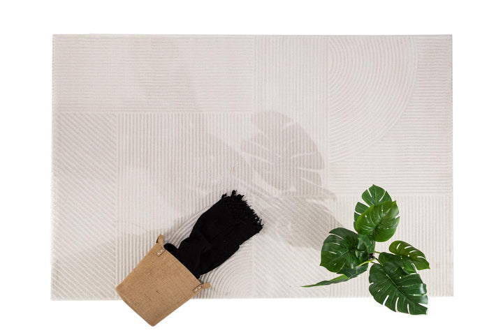 Χαλί Organic Royal Carpet σε cream χρώμα με γεωμετρικά σχέδια, φωτογραφημένο από ψηλά με διακόσμηση καλάθι και φυτό.