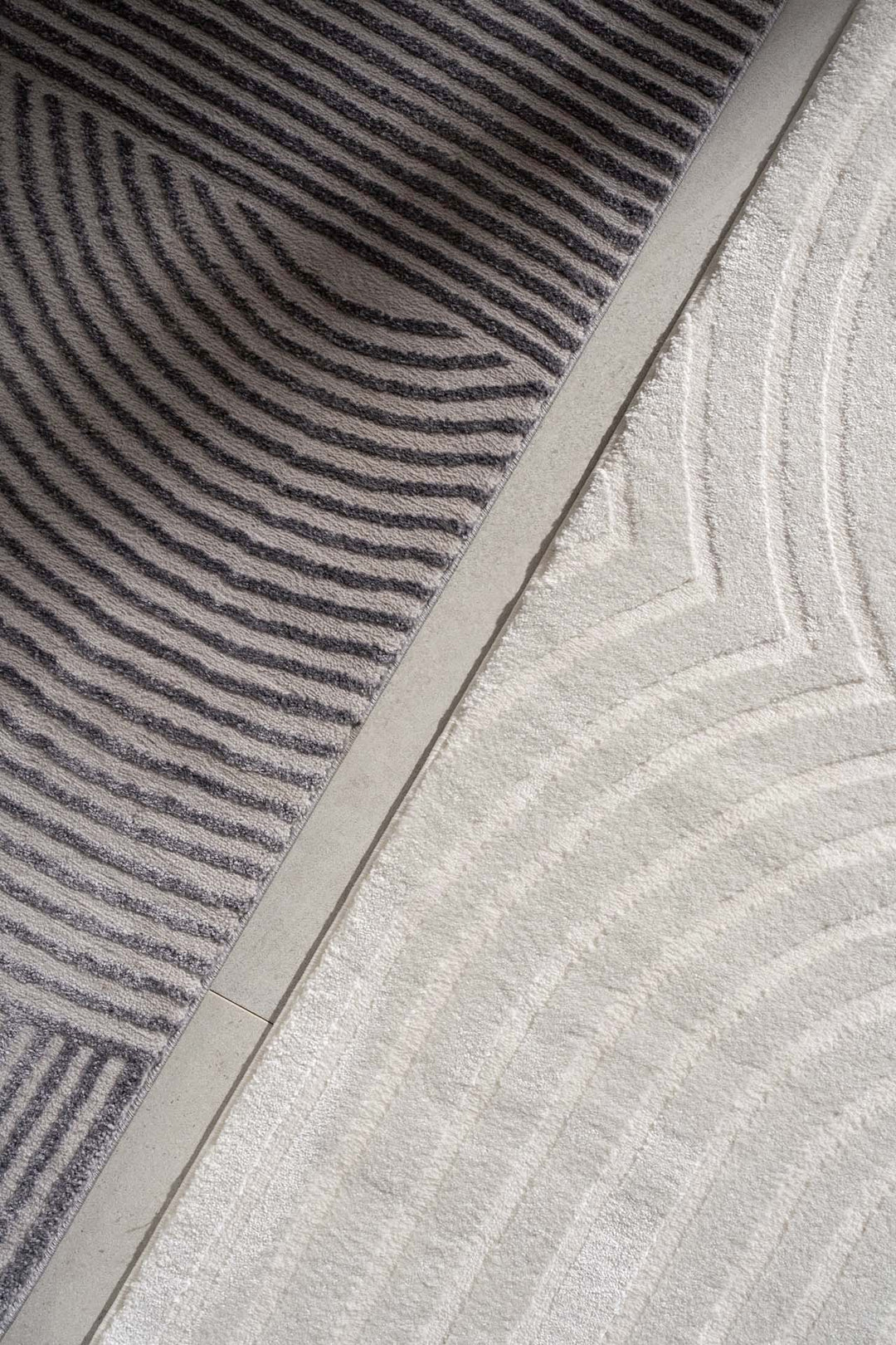 Δίχρωμο χαλί Organic Royal Carpet σε γκρι και εκρού, με κυκλικά και γραμμικά σχέδια, λεπτομέρεια από κοντινή λήψη στο πάτωμα.