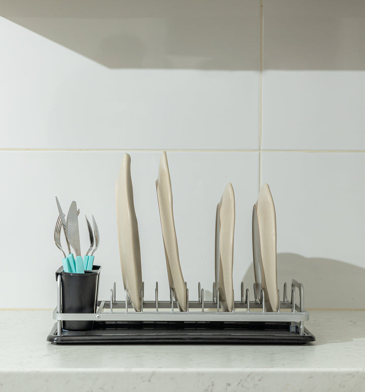 Καθαρή πλάγια όψη (προφίλ) του στεγνωτήρα πιάτων σε πλήρη χρήση, δείχνοντας πώς στέκονται τα πιάτα και τα μαχαίρια κατά το στέγνωμα.