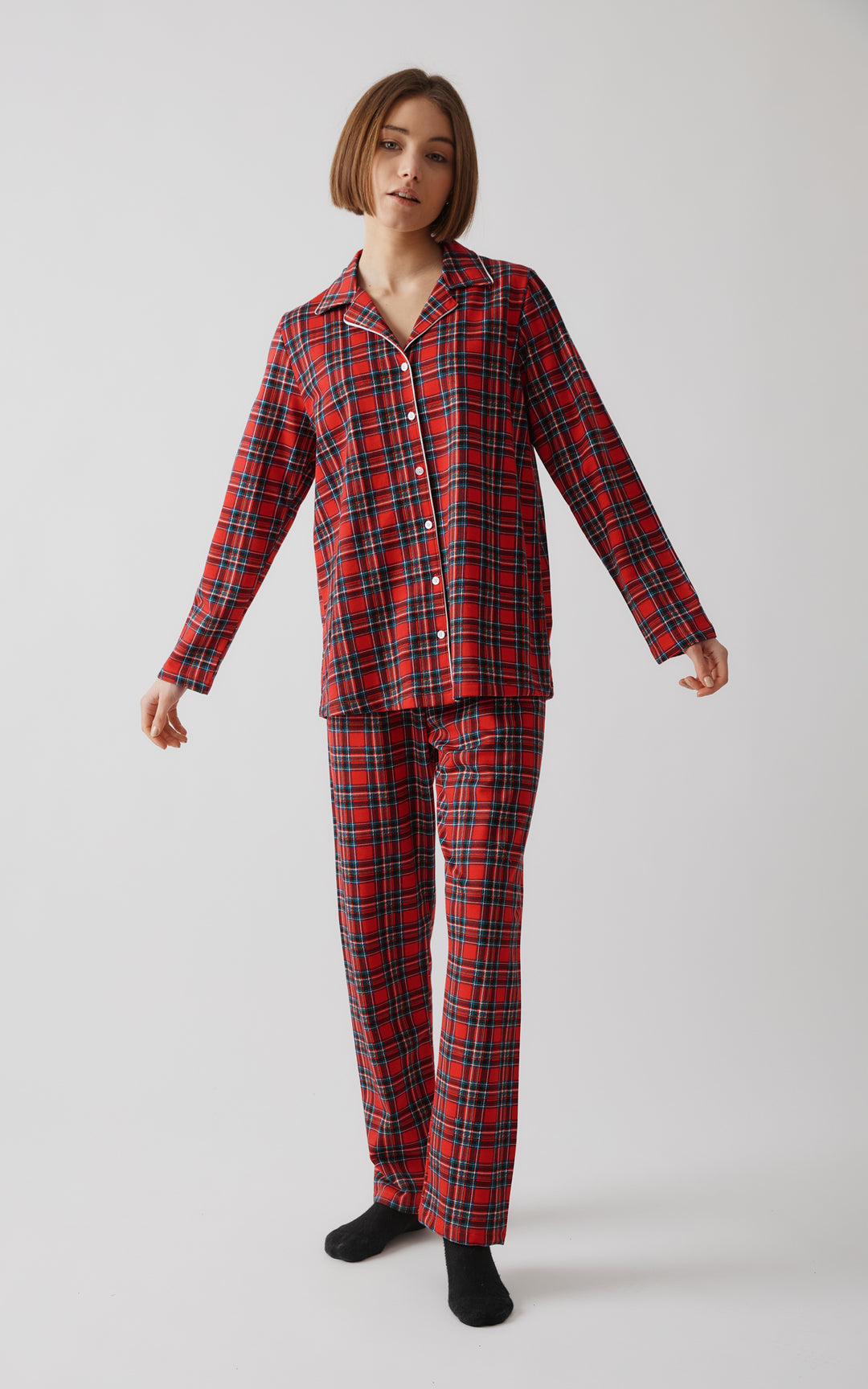 Το μοντέλο ποζάρει όρθιο με ανοιχτή στάση σώματος, ντυμένο με καρό σετ πιτζάμας σε κόκκινο χρώμα, πάνω σε ουδέτερο φόντο.