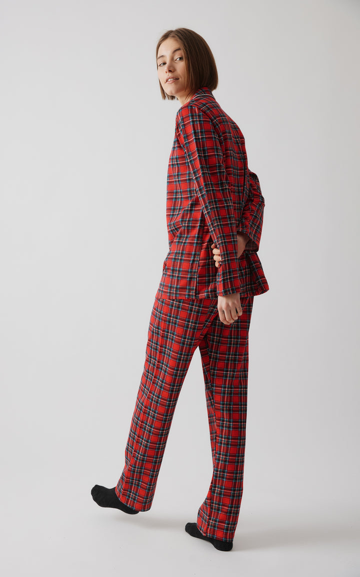 Γυναικείο μοντέλο φωτογραφίζεται από το πλάι ενώ στρέφεται προς την κάμερα, φορώντας κόκκινη καρό πιτζάμα και μαύρες κάλτσες.