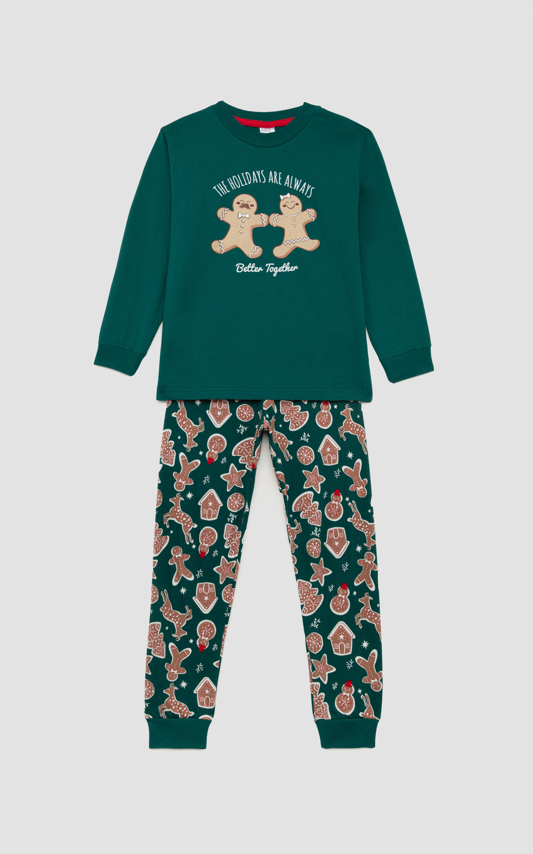 Χριστουγεννιάτικη παιδική πιζάμα σε πράσινο χρώμα με χαρούμενα μπισκοτάκια και παιχνιδιάρικη διάθεση , μπροστά  από απαλο γκρι φόντο. 