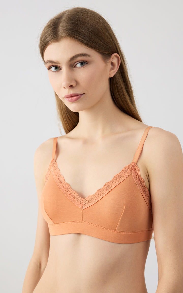 Γυναικείο μοντέλο φοράει πορτοκαλί bralette σουτιέν με λεπτομέρειες δαντέλας, σε καθαρό φωτεινό φόντο minimal αισθητικής.