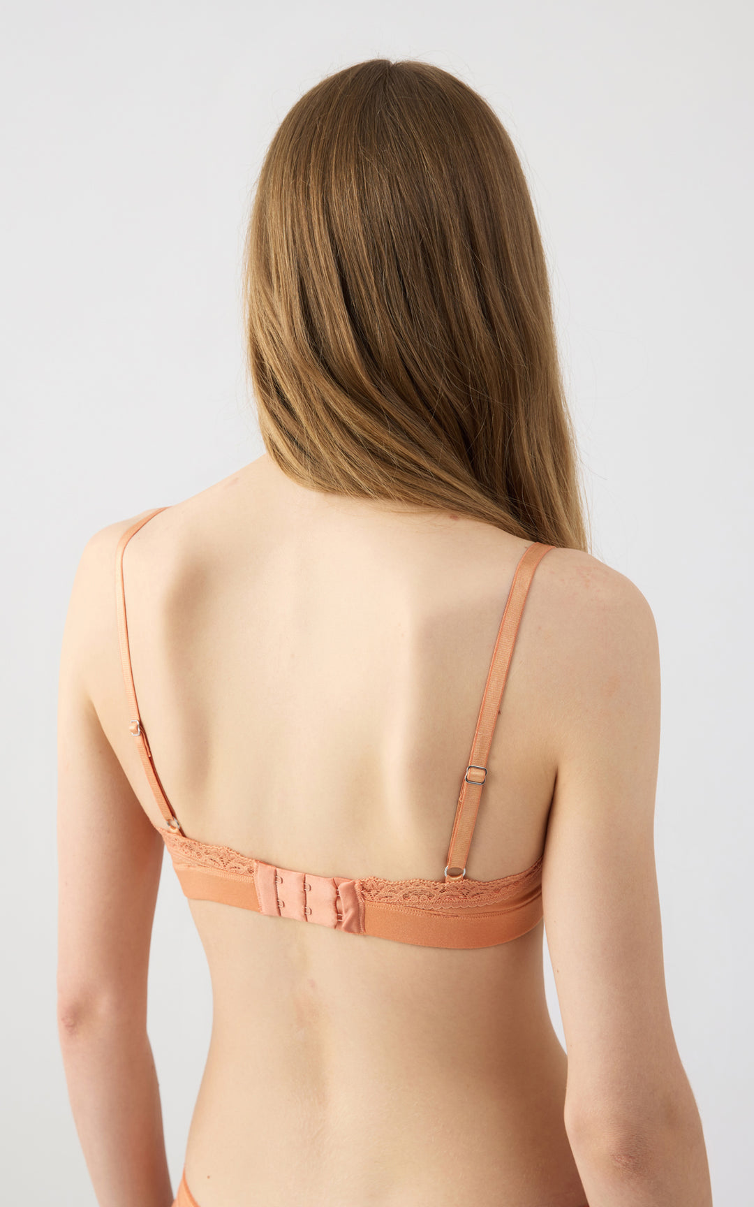 Πίσω όψη πορτοκαλί bralette σουτιέν με ρυθμιζόμενες τιράντες και δαντέλα, φορεμένο σε μοντέλο με ουδέτερο φόντο.