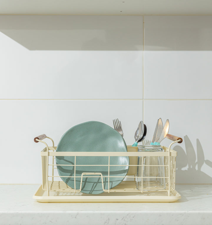 Μετωπική κοντινή λήψη της πιατοθήκης πάνω σε μαρμάρινο πάγκο, γεμάτης με ένα πράσινο πιάτο, ποτήρι και μαχαιροπίρουνα.