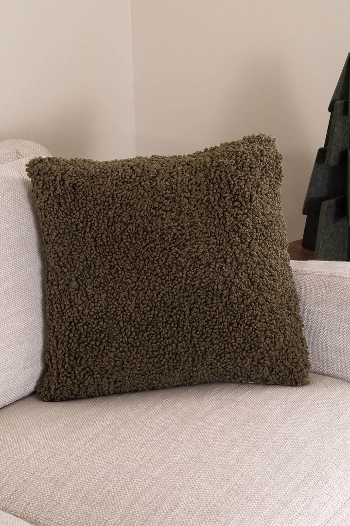 Λαδί γούνινη μαξιλαροθήκη Snug Royal Carpet με σγουρή υφή προβατάκι, ακουμπισμένη σε εκρού καναπέ.
