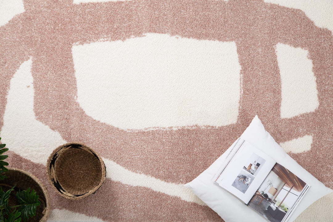 Διακοσμητική σύνθεση πάνω σε χαλί Lilly Royal Carpet με αφηρημένο σχέδιο, ψάθινα καλάθια και λευκό μαξιλάρι.
