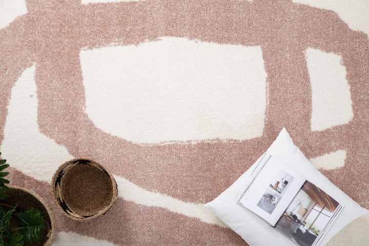 Διακοσμητική σύνθεση πάνω σε χαλί Lilly Royal Carpet με αφηρημένο σχέδιο, ψάθινα καλάθια και λευκό μαξιλάρι.